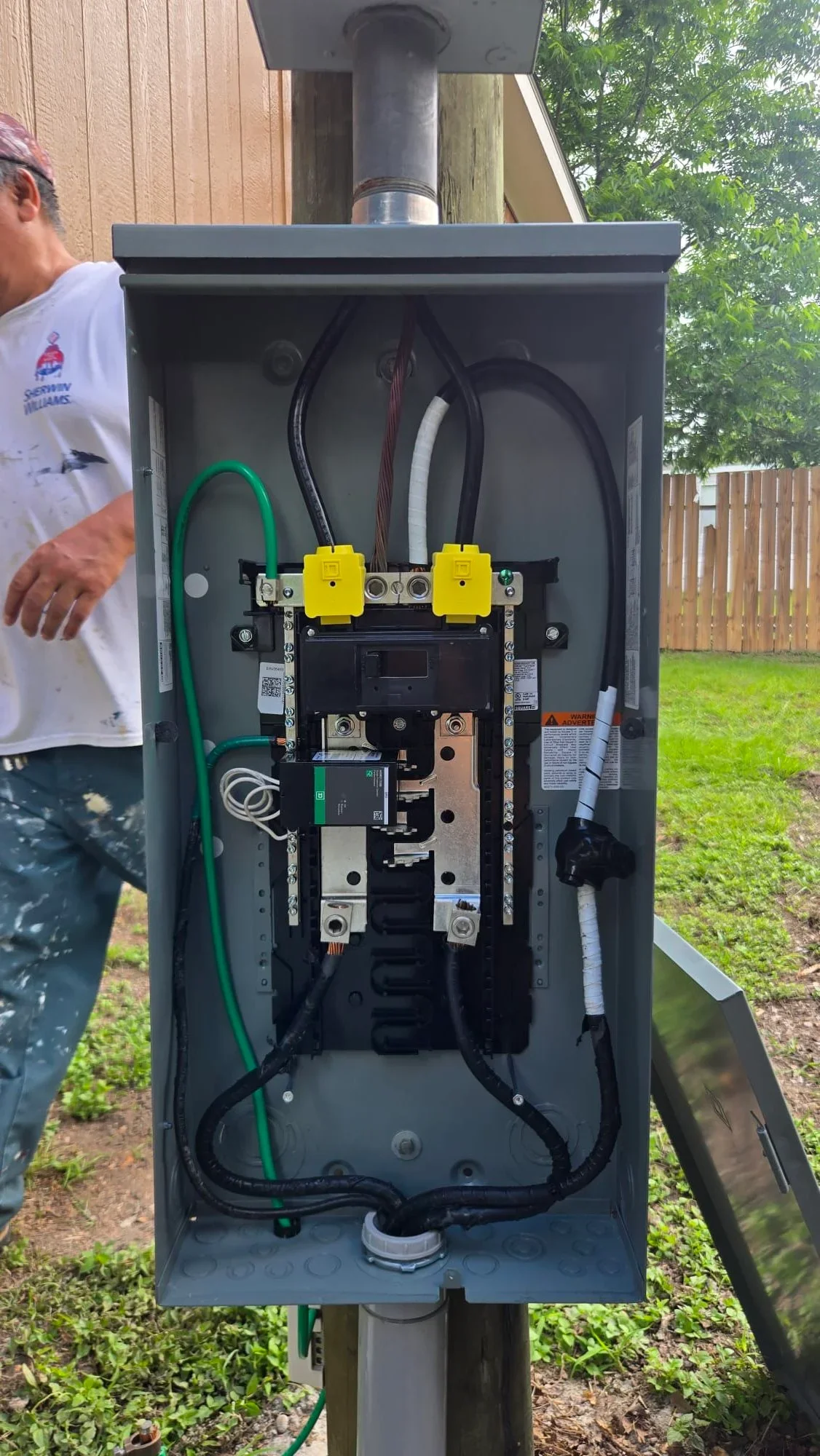Electrical panel with dual breakers, organized wiring, and conduit connection installed on exterior wall
