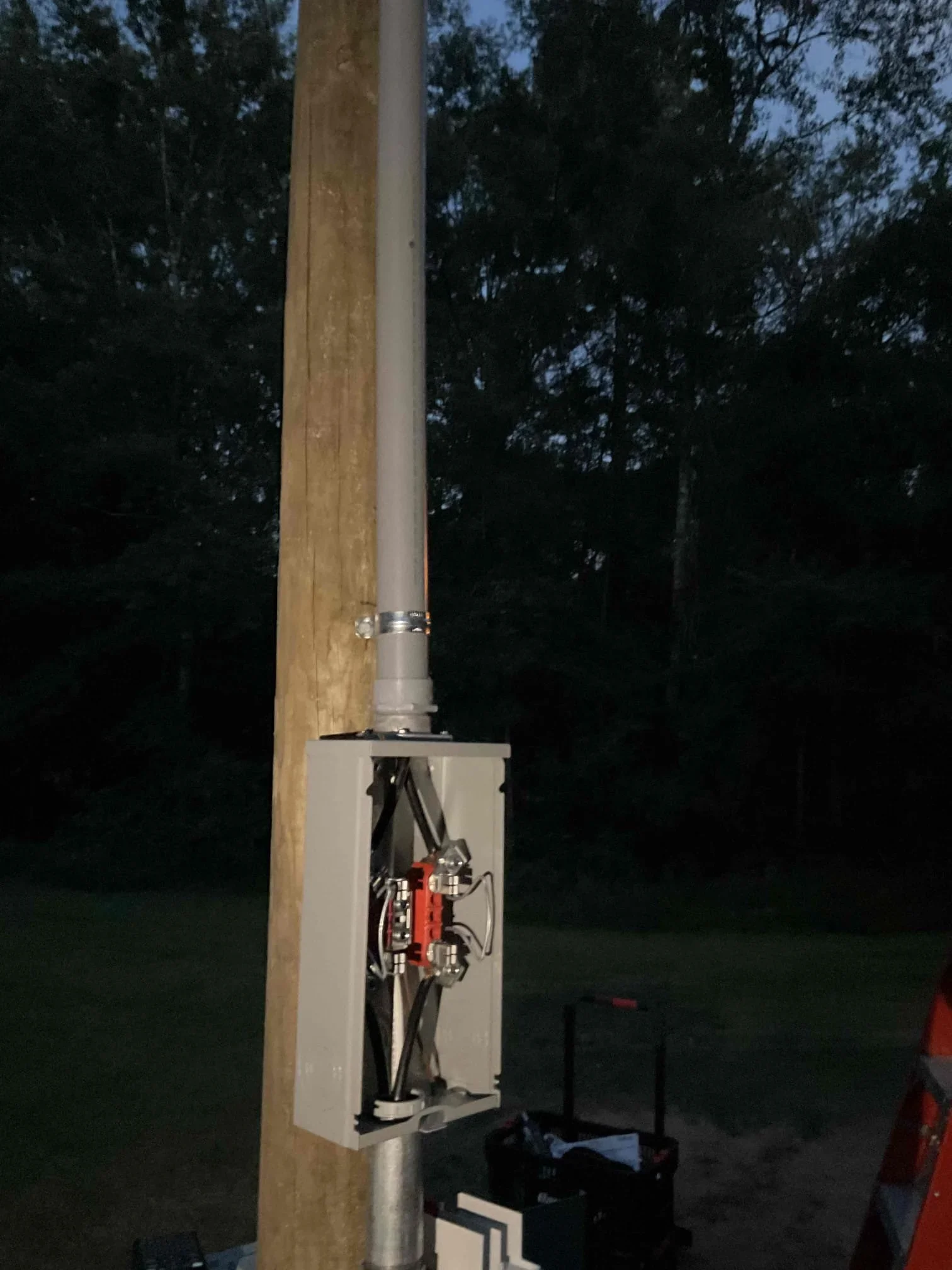 Weatherproof electrical service box with red disconnect switch mounted on wooden post