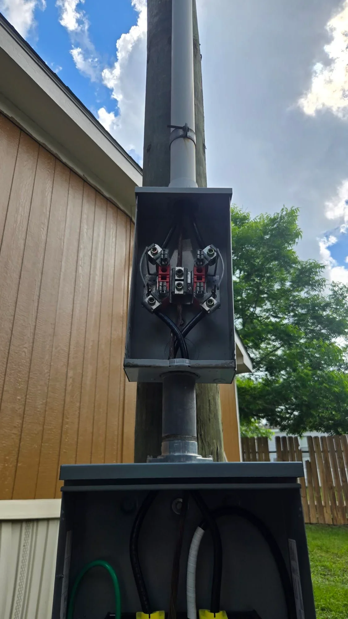 Black electrical panel with four breakers mounted on utility pole with metal conduit