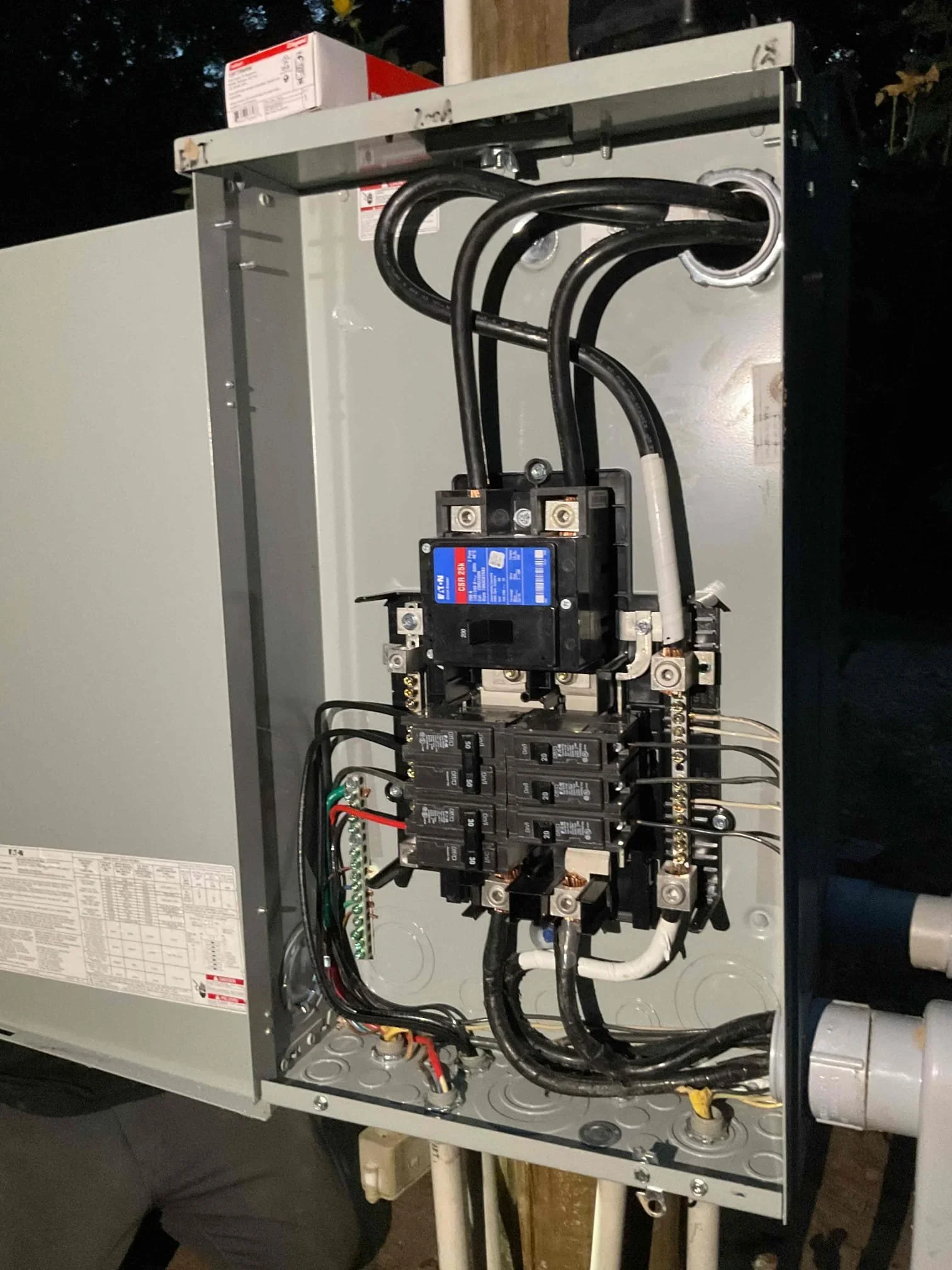 New electrical panel with main disconnect, multiple circuit breakers, and black service conductors installed